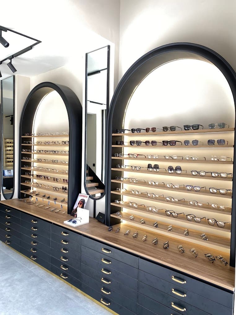 Mur d'exposition Optique Monovision — arches noires et vitrines éclairées